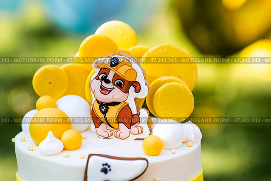 Russia, Moscow, 28 June 2024: Birthday cake at the children's birthday party "Puppy Patrol". Balloons in the background. The concept of a children's holiday in nature. Редакционное фото, фотограф Photojuli / Фотобанк Лори