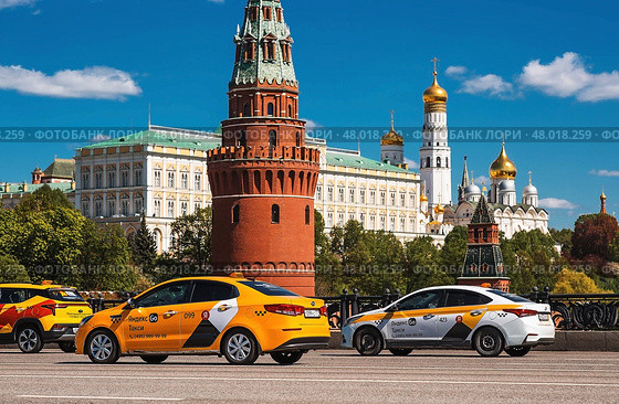 Russia, Moscow, April 28, 2025. Taxi business. A yellow taxi car in motion against the background of the Kremlin in the center of the capital. A trip to the famous sights of Moscow. Редакционное фото, фотограф Photojuli / Фотобанк Лори