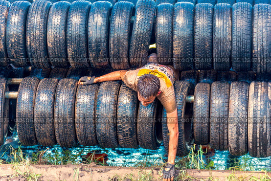 Russia, Samara, June 2019: athletic youth participates in a race of heroes and overcomes obstacles car tires on a summer day in the village of Roshchinsky . Text in Russian: race of heroes, platoon. Редакционное фото, фотограф Акиньшин Владимир / Фотобанк Лори