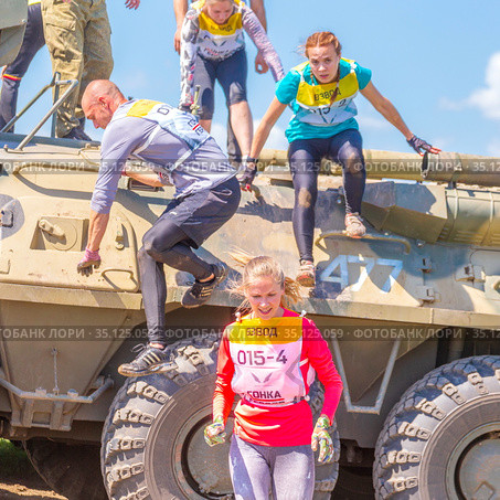 Russia, Samara, June 2019: young athletic people, participants in the hero race, climb through an armored personnel carrier in the village of Roshchinsky near Samara. Text in Russian: race of heroes, platoon. Редакционное фото, фотограф Акиньшин Владимир / Фотобанк Лори