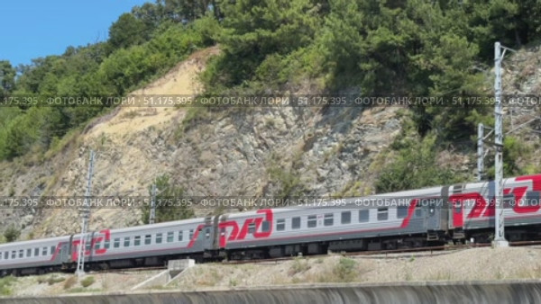 Russia, Sochi, 08/28/2025. A long-distance train moves along the rails along the sea on a sunny day. Стоковое видео, видеограф Васильева Юлия / Фотобанк Лори
