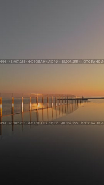 Russia, St.Petersburg, 18 August 2024: an art object in the form of a water cascade with a view on chapel on the island near the port of Hercules at sunset, near skyscraper Lakhta Center. Редакционное видео, видеограф Vladimir Drozdin / Фотобанк Лори