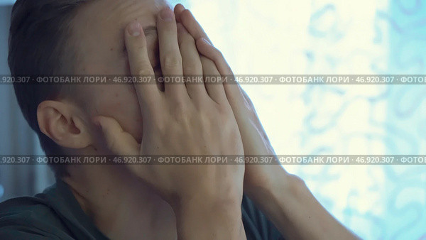 Sad cheerless man, sitting in the room and covering his face. Стоковое фото, фотограф David Kashakhi / Фотобанк Лори