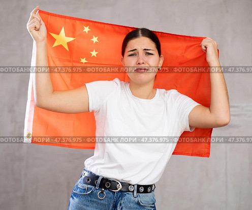 Sad young woman holding China flag against unicoloured background. Стоковое фото, фотограф Яков Филимонов / Фотобанк Лори