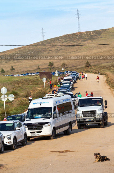 SAKHYURTA VILLAGE, BAIKAL LAKE, OLKHON ISLAND, IRKUTSK REGION, RUSSIA - August 14, 2023: A line of autotourists' cars at the ferry crossing from Olkhon Island after summer vacation. Редакционное фото, фотограф Виктория Катьянова / Фотобанк Лори