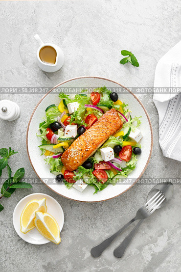 Salmon fish salad. Fresh vegetable greek salad with tomato, pepper, lettuce, olives, cucumbers, feta cheese and grilled salmon fish fillet in bowl, healthy food, omega 3, keto diet, mediterranean cusine, top view. Стоковое фото, агентство Ingram Publishing / Фотобанк Лори