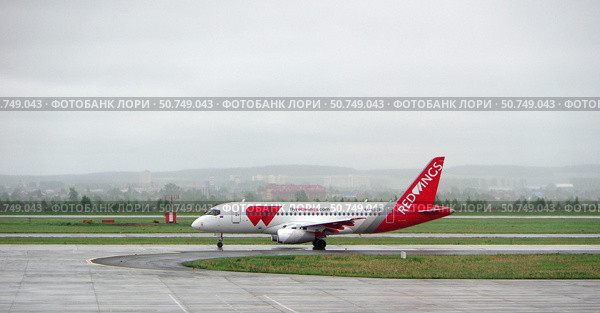 Самолёт Сухой SuperJet 100-95LR в ливрее авиакомпании Red Wings на рулежной дорожке аэропорта Кольцово. Екатеринбург, Россия (2021 год). Редакционное фото, фотограф Алексей Иванов / Фотобанк Лори