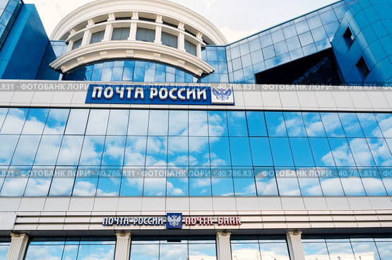 Saransk, Mordovia, Russia, 4.06.2023. The blue facade of the building with the inscription Russian Post and a double-headed Russian eagle, against the background of the reflection of clouds on the glass surface. Редакционное фото, фотограф Оксана Медведева / Фотобанк Лори