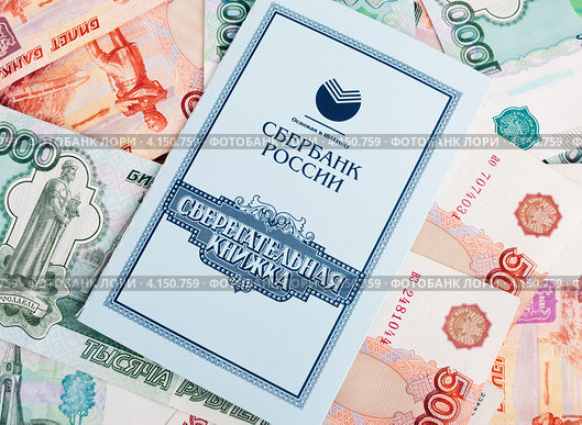 Сберегательная книжка лежит на российских деньгах (2012 год). Редакционное фото, фотограф Игорь Низов / Фотобанк Лори