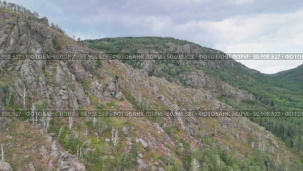 Scenic landscape featuring steep mountains and dense forests in a valley, with dramatic cloud formations above, highlighting the tranquility of the natural environment. Стоковое видео, видеограф Ирина Ручушкина / Фотобанк Лори