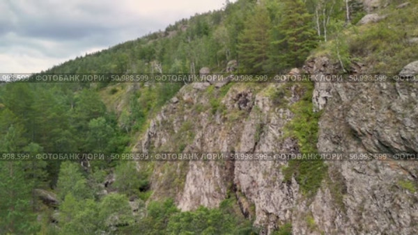Scenic landscape featuring steep mountains and dense forests in a valley, with dramatic cloud formations above, highlighting the tranquility of the natural environment. Стоковое видео, видеограф Ирина Ручушкина / Фотобанк Лори