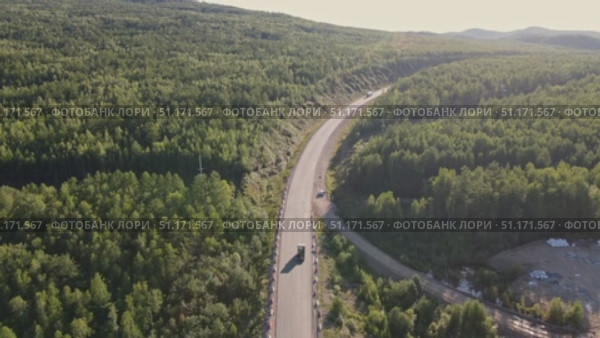 Scenic overview of winding road through lush forest in remote area. Стоковое видео, видеограф Гурьянов Андрей / Фотобанк Лори