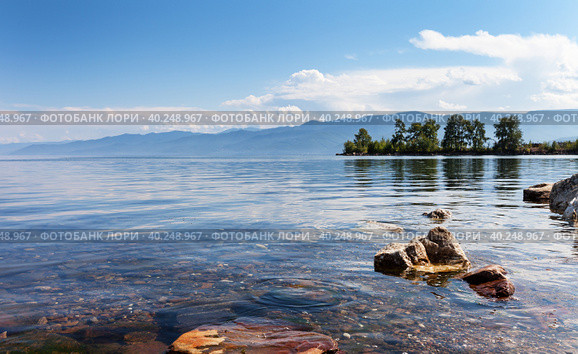 Scenic summer landscape of southern tip of Baikal Lake in Kultuk village on sunny day. View of Shamansky Cape peninsula and bay with blue water against backdrop of Khamar-Daban mountains range. Стоковое фото, фотограф Виктория Катьянова / Фотобанк Лори