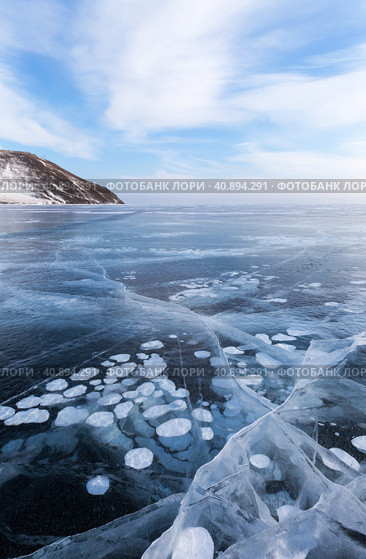 Scenic winter landscape of frozen Baikal Lake in cold winter day. Natural seasonal background with blue ice cover with white bubbles and cracks.  Winter ice travel and active outdoors. Стоковое фото, фотограф Виктория Катьянова / Фотобанк Лори