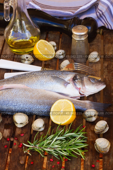 Seabass. Two Seabass raw fish on wooden table . Стоковое фото, агентство Ingram Publishing / Фотобанк Лори