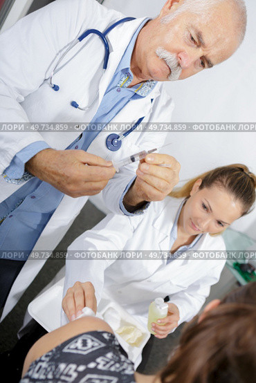 senior doctor injecting patient with syringe to collect blood. Стоковое фото, агентство Ingram Publishing / Фотобанк Лори
