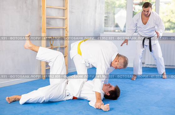 Senior man, karate sensei, engaging kumite with young guy in training room. Стоковое фото, фотограф Яков Филимонов / Фотобанк Лори