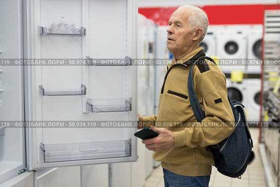 senor man pensioner buying fridge in showroom of electrical appliance store. Стоковое фото, фотограф Татьяна Яцевич / Фотобанк Лори