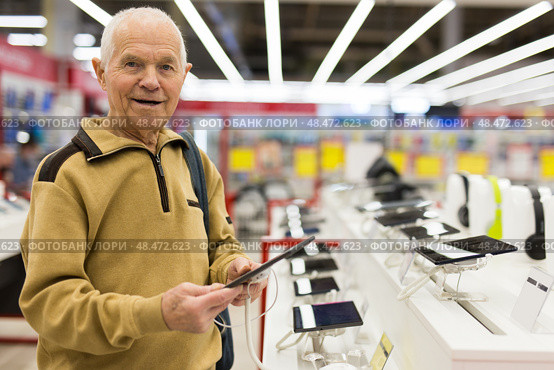 Senor man pensioner buying modern tablet digital in showroom of digital electronic goods store. Стоковое фото, фотограф Татьяна Яцевич / Фотобанк Лори