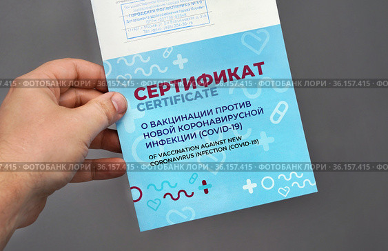 Сертификат о вакцинации против новой коронавирусной инфекции (COVID-19) в руке мужчины (2021 год). Редакционное фото, фотограф Dmitry29 / Фотобанк Лори