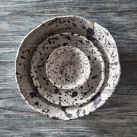 Set of porcelain handcraft plates or bowls, one inside the other on a gray wooden table. Traditional ceramic vintage handmade dishes. Top view. Clay handcraft empty gray bowls, covered with glazed a gray wooden background with copy space. Flat lay. Стоковое фото, агентство Ingram Publishing / Фотобанк Лори