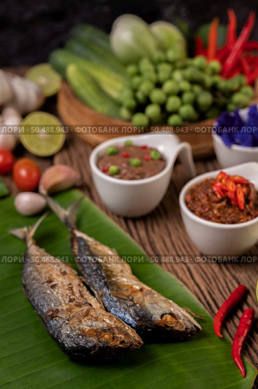 Shrimp paste, mackerel, fried on banana leaves, chili, tomato, garlic and lemon on wooden floor. Стоковое фото, агентство Ingram Publishing / Фотобанк Лори