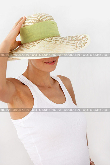 Shy woman pushing hat over face. Стоковое фото, агентство Ingram Publishing / Фотобанк Лори