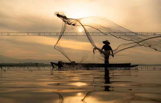 Silhouette of fisherman at sunrise, Standing aboard a rowing boat and casting a net to catch fish for food. Стоковое фото, агентство Ingram Publishing / Фотобанк Лори