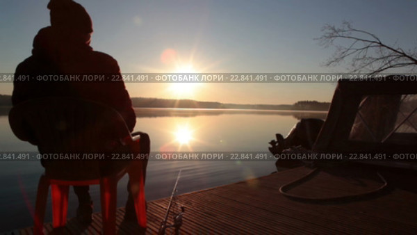 Силуэт рыбака на пирсе в лучах утреннего солнца, рыбалка на озере. Стоковое видео, видеограф Кекяляйнен Андрей / Фотобанк Лори