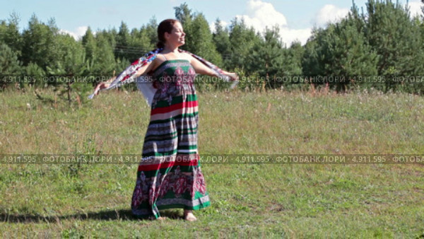 Симпатичная женщина в сарафане и с платком кружится в танце на летнем лугу. Стоковое видео, видеограф Кекяляйнен Андрей / Фотобанк Лори