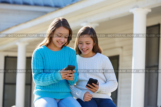 Sister twins having fun with technology mobile smartphone. Стоковое фото, агентство Ingram Publishing / Фотобанк Лори