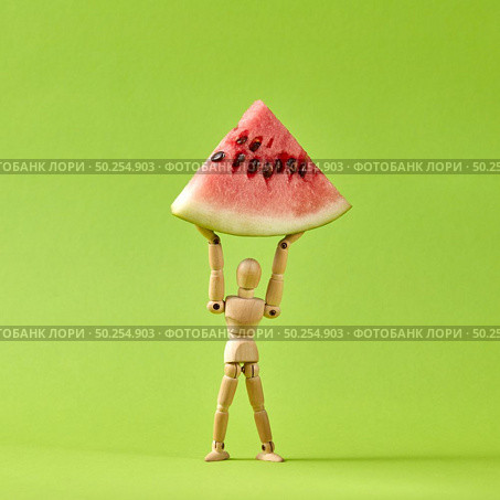 Slice of ripe fresh natural organic water malon in the hands of movable human miniatures model on a lawn green background with copy space.. Energy wooden mannequin model holds slice of ripe water melon. Стоковое фото, агентство Ingram Publishing / Фотобанк Лори