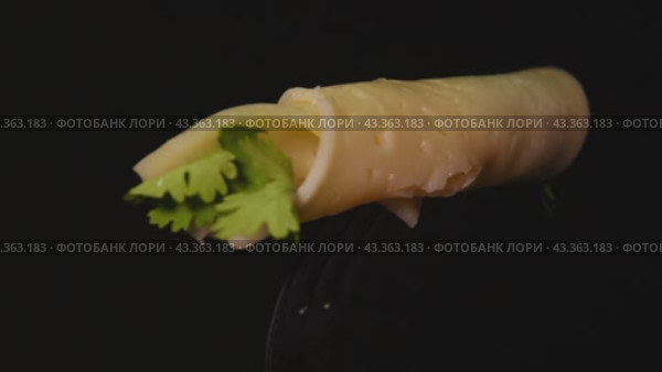 Sliced cheese with herbs rotates on a dark background. Close-up. Стоковое видео, видеограф Ярославский Максим / Фотобанк Лори