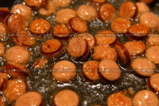 Slices of fried bangers in a frying pan. Farm, organic products. Homemade grilled pork barbecue sausages in an iron pan. Top view. Cooking Sausages. Roasted wurst, wiener. Full English breakfast. Стоковое фото, фотограф Марина Демидюк / Фотобанк Лори
