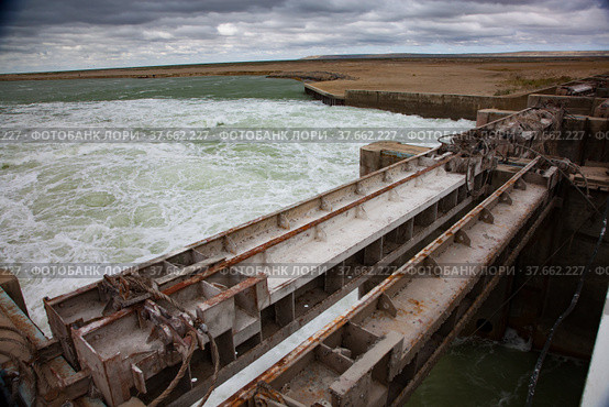 Small Aral Sea Kok-aral dam. Kazakhstan, Kyzylorda region. Concrete supports, metal shutters. turbulent water after dam. Grey storm sky. Стоковое фото, фотограф Alexey Rezvykh / Фотобанк Лори