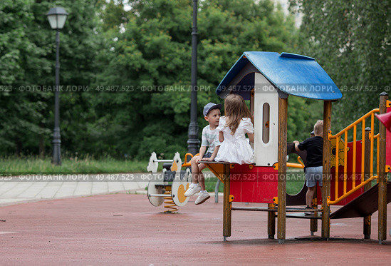 Small children play on the playground. A girl and a boy are having fun playing outside on a sunny spring day. Childhood and child development. Стоковое фото, фотограф Photojuli / Фотобанк Лори