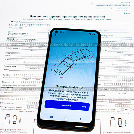 Смартфон с открытым приложением "Госуслуги-авто" на бланке извещения о дорожно-транспортном происшествии. Стоковое фото, фотограф Анна Аникова / Фотобанк Лори
