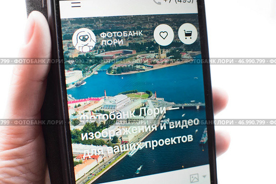 Смартфон с открытым сайтом фотобанка Лори в руке. Редакционное фото, фотограф Алиса Сокол / Фотобанк Лори
