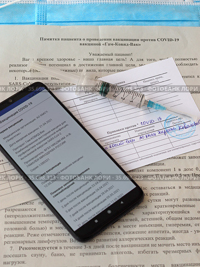Смартфон с открытым сайтом государственных услуг, медицинский шприц, сертификат о проведении вакцинации против COVID-19 (2021 год). Редакционное фото, фотограф Цибаев Алексей / Фотобанк Лори