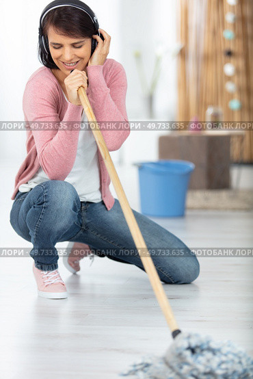 smiling excited young housewife havig fun with vacuum cleaner. Стоковое фото, агентство Ingram Publishing / Фотобанк Лори