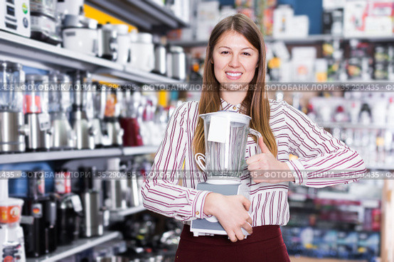 Smiling girl seller showing liquidiser in shop. Стоковое фото, фотограф Яков Филимонов / Фотобанк Лори