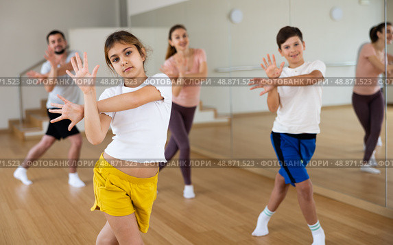 Smiling teenage girl enjoying active dance with family in studio. Стоковое фото, фотограф Яков Филимонов / Фотобанк Лори