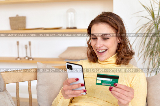Smiling woman paying by card for online purchase by phone. Стоковое фото, фотограф Ekaterina Demidova / Фотобанк Лори
