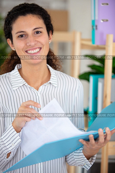 smiling young woman holding an open ring binder. Стоковое фото, агентство Ingram Publishing / Фотобанк Лори