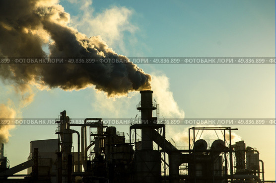 Smoking chimney  at sunset on industrial buildings complex. Стоковое фото, агентство Ingram Publishing / Фотобанк Лори