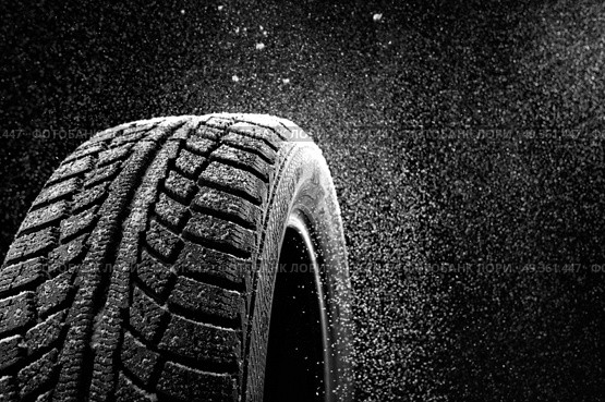 Snow sweeps up a winter tyre cover on a black background. Rubber in snow. Стоковое фото, агентство Ingram Publishing / Фотобанк Лори