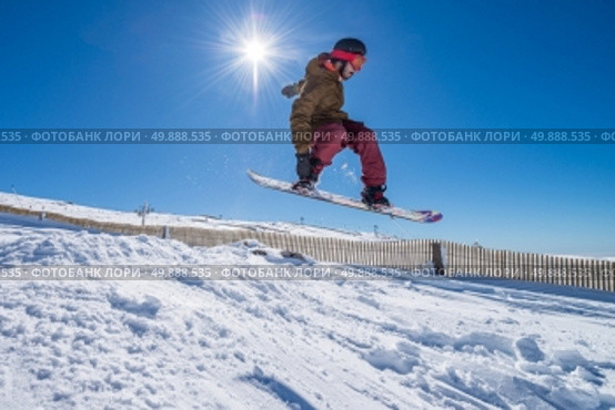 Snowboarder executing a radical jump against blue sky. Стоковое фото, агентство Ingram Publishing / Фотобанк Лори