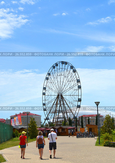 SOCHI, RUSSIA - June 18, 2017: Family goes to Ferris wheel in Sochi Park, which entered the TOP-25 of the best parks in Europe in 2016. Редакционное фото, фотограф Анна Мартынова / Фотобанк Лори