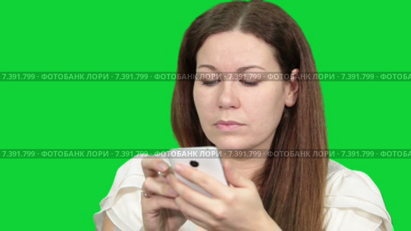 Сосредоточенная женщина смотрит на экран смартфона, читает текст. Зеленый изолированный фон. Стоковое видео, видеограф Кекяляйнен Андрей / Фотобанк Лори