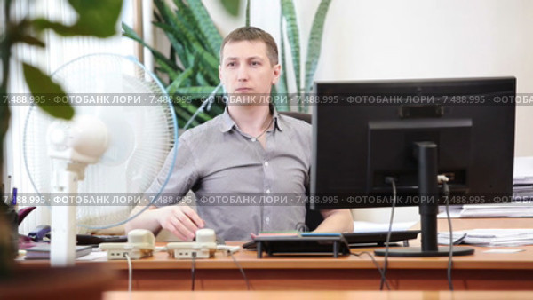 Сотрудник офиса расстегивает рубашку и включает вентилятор на большую скорость вращения, отсутствие кондиционера. Стоковое видео, видеограф Кекяляйнен Андрей / Фотобанк Лори